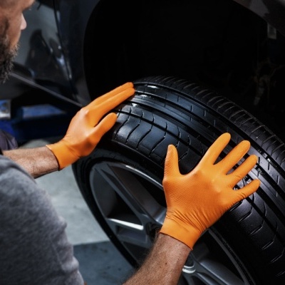 Pessoa com luvas a montar pneu numa oficina automóvel