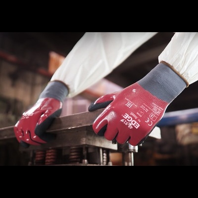 Luvas vermelhas e cinzas com texto branco segurando peça metálica em ambiente industrial