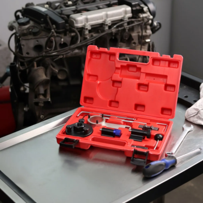 Estojo de ferramentas aberto vermelho com várias peças de metal e plástico em superfície metálica