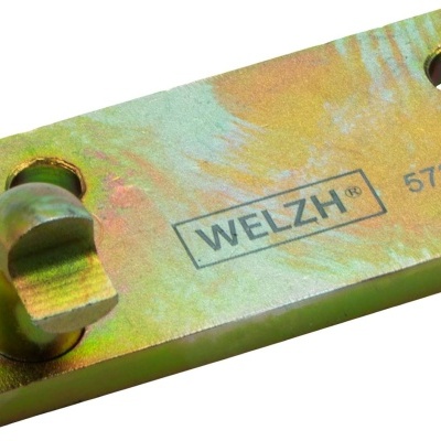 Peça metálica retangular com dois orifícios e relevo cilíndrico amarelo esverdeado