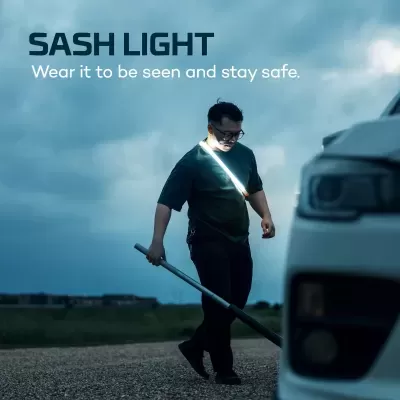 Homem com faixa luminosa branca perto de carro branco em estrada ao entardecer