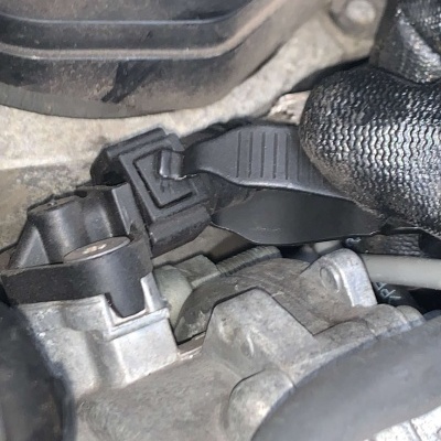 Conector elétrico preto em componente metálico cinzento de motor com luva preta