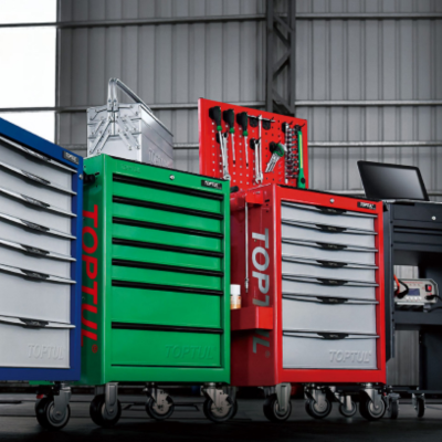 Carrinhos de ferramentas metálicos verdes e vermelhos com gavetas e ferramentas no fundo de oficina