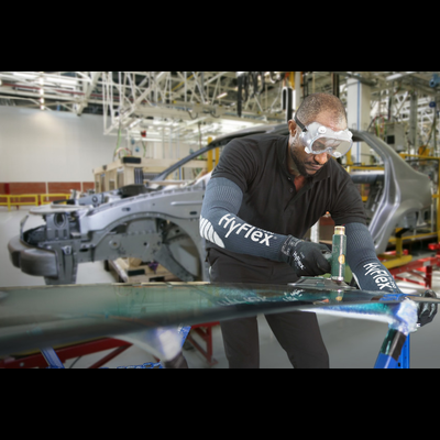 Trabalhador com luvas e óculos de segurança monta vidro automóvel numa fábrica de carros