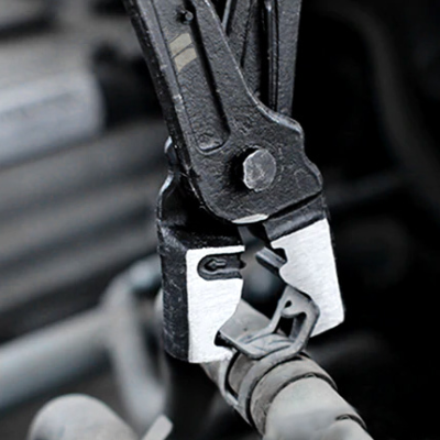 Alicate de metal preto e prateado segurando tubo cinza num ambiente industrial
