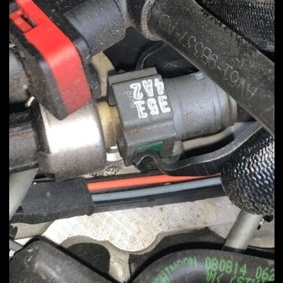 Conector elétrico preto e vermelho em componente automóvel com mangueiras e cabos ao redor