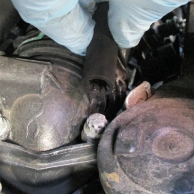 Motor de automóvel com mão de luva a segurar peça de borracha preta