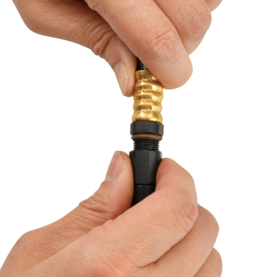 Mãos segurando uma válvula metálica preta e dourada