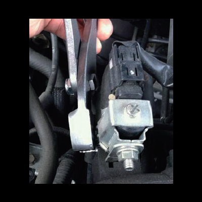 Peça metálica prateada com parafusos num motor de carro