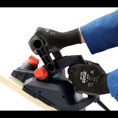 Plaina elétrica cinza e preto com botões vermelhos nas mãos com luvas pretas