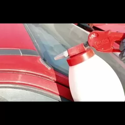 Frasco branco com tampa vermelha e aplicador próximo a superfície metálica vermelha