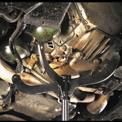 Cárter de óleo de motor de automóvel sujo suportado por macaco hidráulico