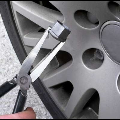 Alicate de anel de trava junto à jante cinzenta de uma roda de carro