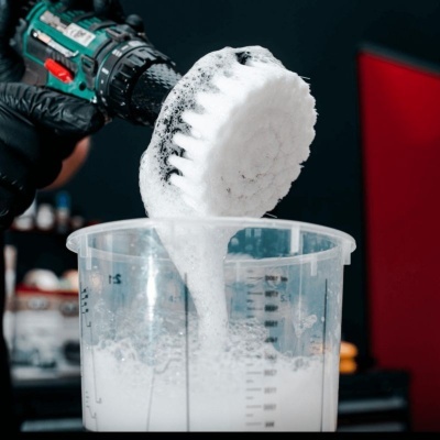 Escova de limpeza branca com espuma num recipiente transparente