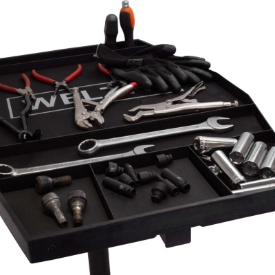 Bandeja preta com ferramentas variadas, luvas e a palavra DEWEL ao fundo