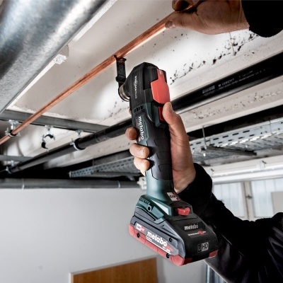 Pessoa a usar ferramenta elétrica preta e vermelha a trabalhar em tubo de cobre no teto