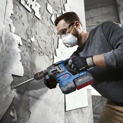 Homem a usar martelo perfurador elétrico para remover material de parede descascada