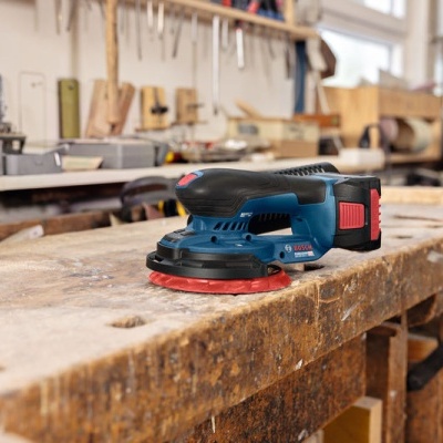 lixadora elétrica azul e preta numa bancada de madeira numa oficina