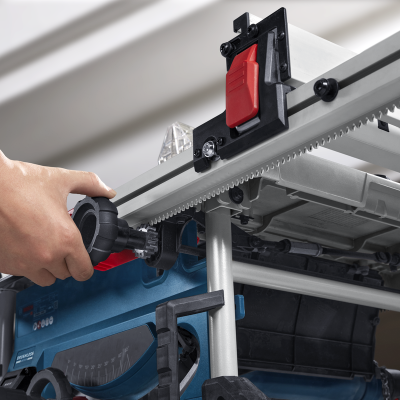 Mesa de serra elétrica azul e cinza com régua milimetrada e ajuste, mão a operar