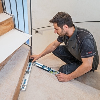 Homem a usar nível de bolha numa escada de madeira interior