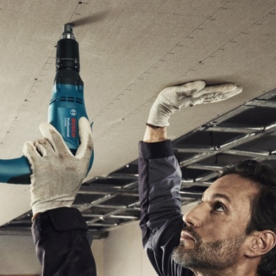 Homem a usar ferramenta elétrica para instalar teto com estrutura metálica