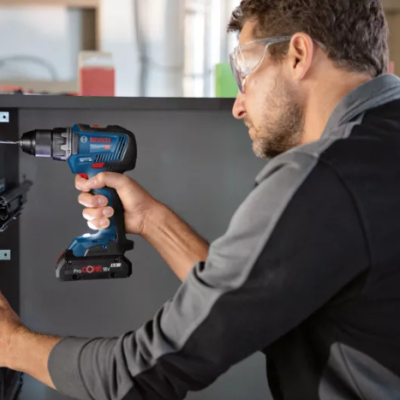 Pessoa a usar furadeira eléctrica Bosch para trabalhar numa porta