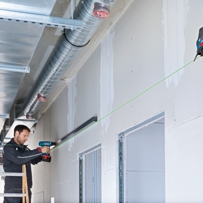 Homem a usar medidor a laser Bosch numa parede interior branca