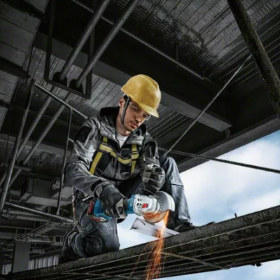 Homem com equipamento de segurança a usar rebarbadora elétrica num ambiente industrial