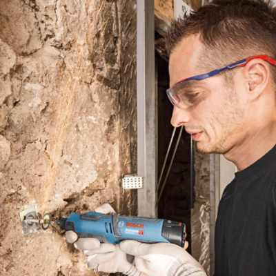 Homem a trabalhar com ferramenta elétrica Bosch numa parede de pedra