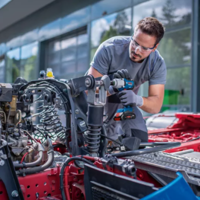 Homem a usar ferramenta elétrica na reparação de estrutura vermelha de veículo grande