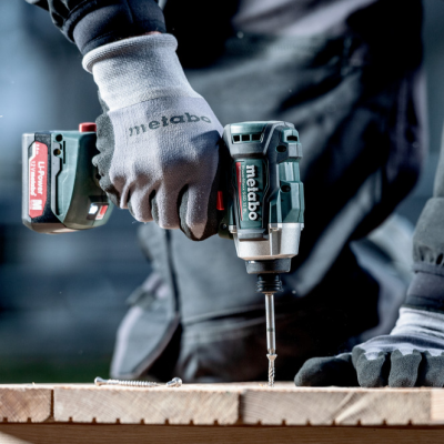 Pessoa com luvas usando furadeira Metabo para perfurar madeira