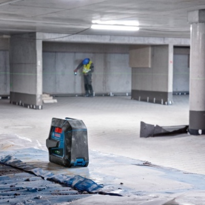 Laser de medição Bosch num ambiente industrial com trabalhador ao fundo