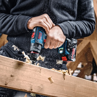 Pessoa a usar furadeira Bosch azul e preta para trabalhar em madeira