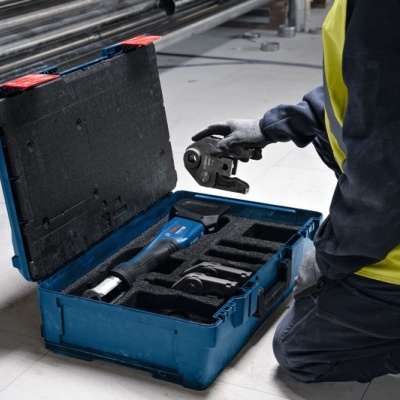 Mala de ferramentas azul aberta com ferramentas organisadas e pessoa a segurar ferramenta elétrica negra e azul