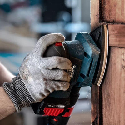 Pessoa lixando porta de madeira com lixadeira elétrica usando luva protetora