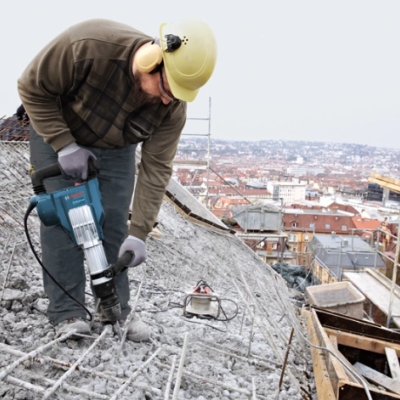 Operário a trabalhar com martelo demolidor num canteiro de obras
