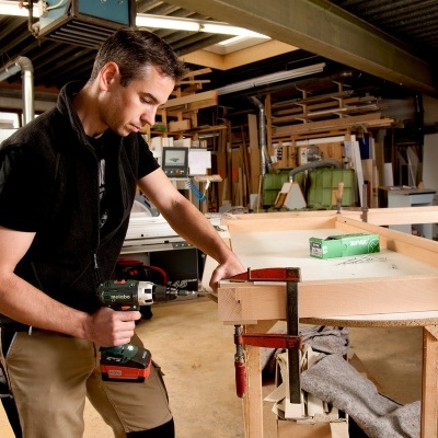 Homem a aparafusar madeira numa oficina de carpintaria