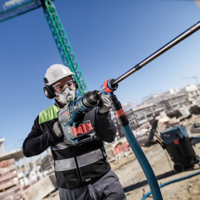Trabalhador com ferramenta elétrica e equipamento de proteção em estaleiro de construção