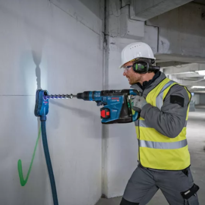Homem usando furadeira para perfurar parede num local de construção
