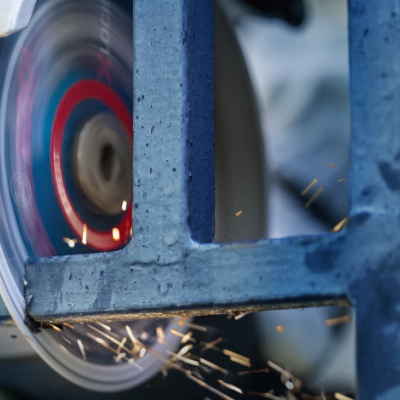 Rebarbadora elétrica a cortar uma estrutura metálica azul com faíscas