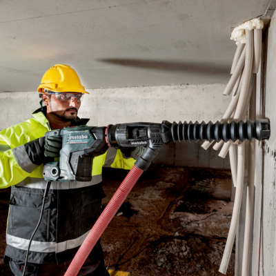 Homem a usar ferramenta elétrica para perfurar parede de construção