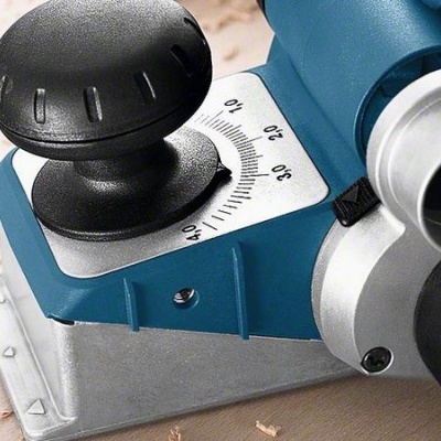 Triturador de madeira Bosch azul e preto sobre madeira clara com aparas