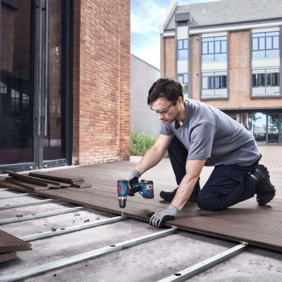 Homem a instalar tábuas de madeira numa área exterior urbana