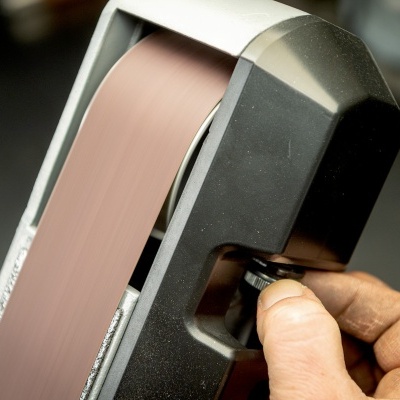 Aparelho portátil de polimento com fita abrasiva castanha e corpo preto