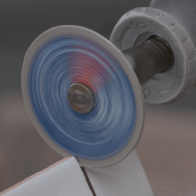 Ferramenta elétrica a cortar peça branca com lâmina azul em rotação