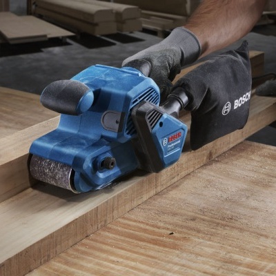 Lixadora elétrica Bosch azul em uso sobre madeira em oficina