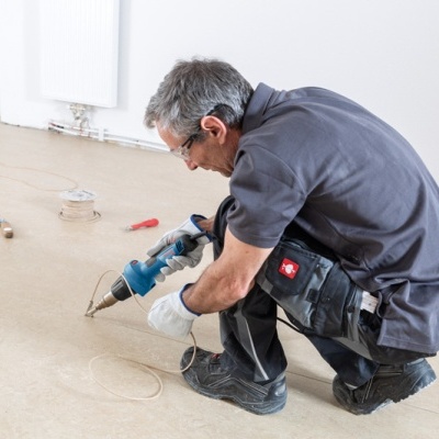 Homem a usar ferramenta elétrica num piso interior branco