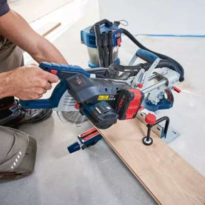 Máquina de corte de madeira azul escuro e preto a cortar tábua clara