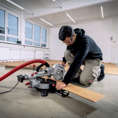 Homem a cortar madeira com serra circular num espaço interior