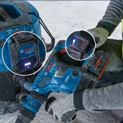 Furadeira/perfuradora azul Bosch com bateria vermelha em ambiente de construção poeirento